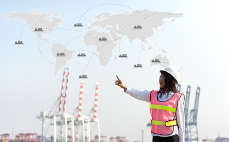 The women engineer working with container Cargo freight ship in shipyard at dusk for Logistic Import...