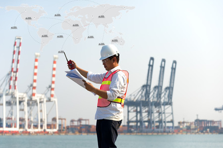 The man engineer working with container Cargo freight ship in shipyard at dusk for Logistic Import...