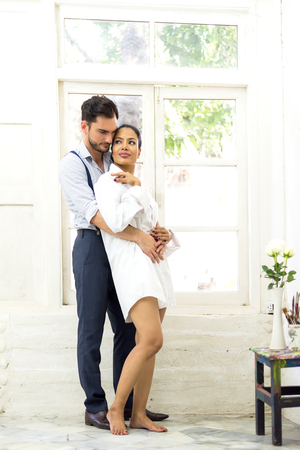 Happiness and romantic scene of love asian couples partners making eye contact in the white roomの写真素材