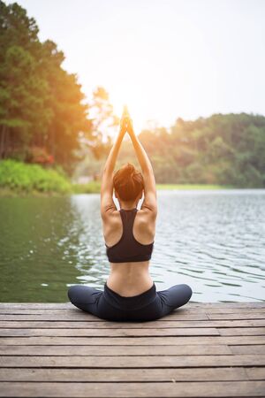 Healthy woman practicing yoga on the bridge in the natureの写真素材