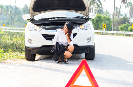 Business woman with a broken car calling for assistanceの写真素材