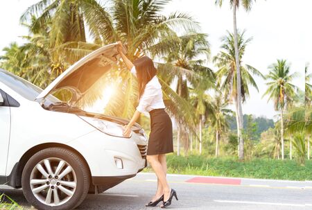 Business woman standing by broken car and looking to engineの写真素材