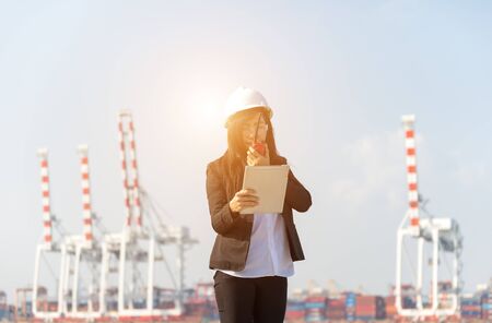 The women engineer working with container Cargo freight ship in shipyard at dusk for Logistic Import Export backgroundの写真素材
