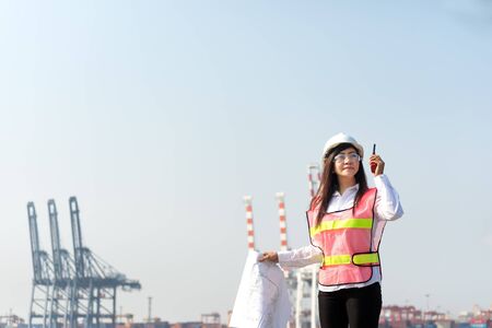 The women engineer working with container Cargo freight ship in shipyard at dusk for Logistic Import Export backgroundの写真素材