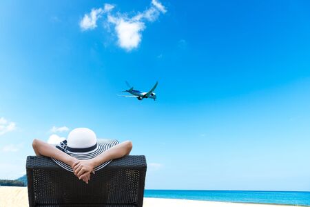 Young woman relaxing and see airplane on beautiful beachの写真素材