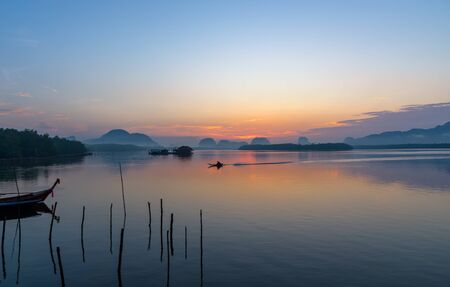 Beautiful sunrise landscape view of fisherman and wooden boat in early morming at Samchong-tai fishing village in Phang-Nga,Thailandの写真素材