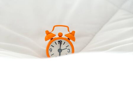 Alarm clock on bed in morning with sun lightの写真素材