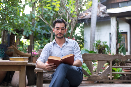 Young relaxed man reading book in natureの写真素材