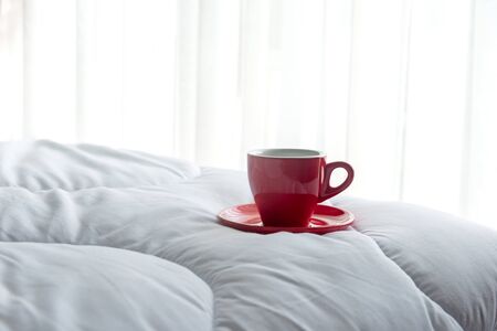 Fresh morning coffee in red cup on the bed.の写真素材
