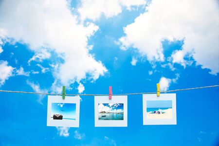 Vacation photos hanging on a rope, background the skyの写真素材