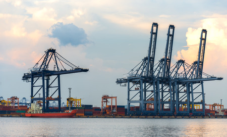 Container Cargo freight ship with working crane bridge in shipyard at dusk for Logistic Import Export background,の写真素材