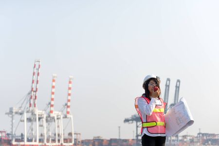 The women engineer working with container Cargo freight ship in shipyard at dusk for Logistic Import Export backgroundの写真素材