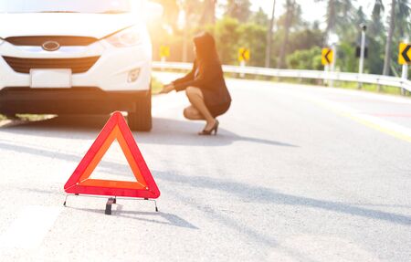 Business women driver changing tyre on her broken car.の写真素材