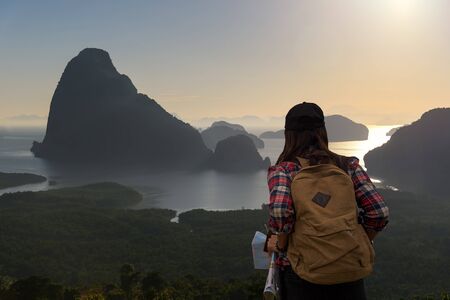 Women traveler with backpack checks map to find directions in wilderness areaの写真素材
