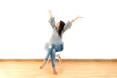 Attractive Asian girl sitting on white modern chair and relax at homeの写真素材