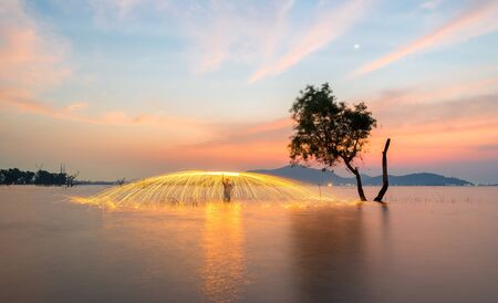 Showers of hot glowing sparks from spinning steel wool near the alone treeの写真素材