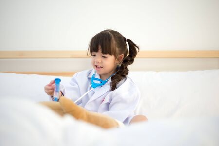 Cute kid girl playing doctor with plush toy at homeの写真素材