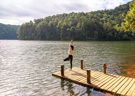 Healthy woman practicing yoga on the bridge in the natureの写真素材