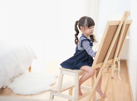 Cute little girl drawing on chalkboard at homeの写真素材