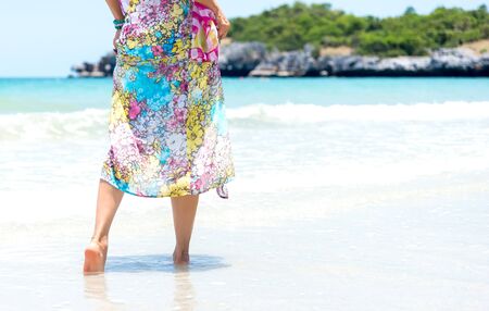 Woman walks towards the beautiful beachの写真素材