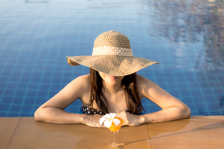 Happy smiling woman with straw hat in swimming poolの写真素材