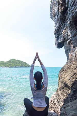 Caucasian woman practicing yoga in a cave near the seaの写真素材