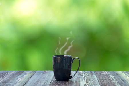 Hot coffee with in back cup on wood table and nature bokeh backgroundの写真素材