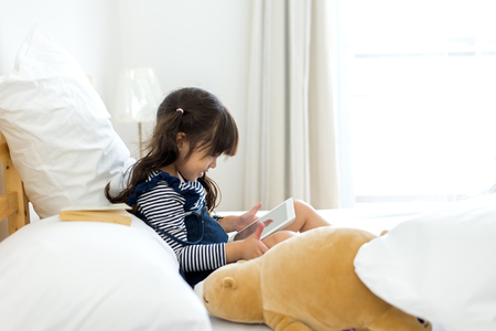 Cute girl looking laptop on bed, education conceptの写真素材