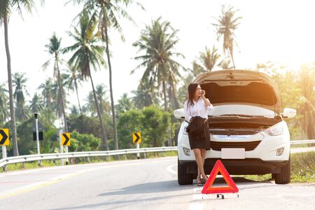 Business woman with a broken car calling for assistanceの写真素材