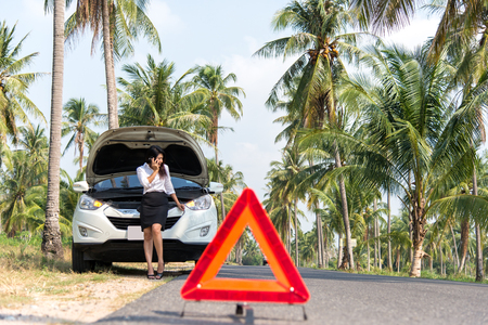 Business woman with a broken car calling for assistance.の写真素材