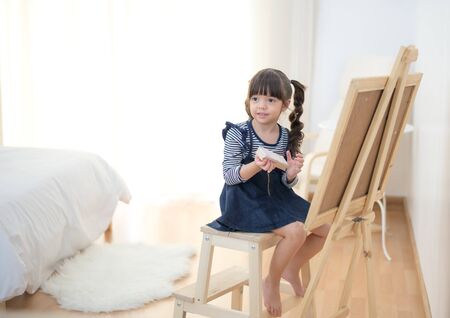 Cute little girl drawing on chalkboard at homeの写真素材