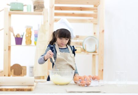 Beautiful child girl are cooking cookies and having fun in the kitchen.の写真素材