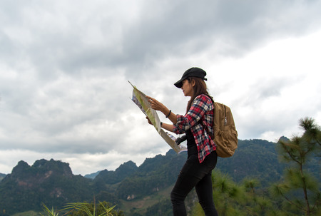 Women traveler with backpack checks map to find directions in wilderness areaの写真素材