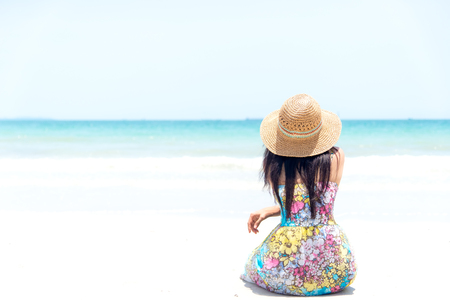 Young woman sitting on the beach looking at the sea and skyの写真素材