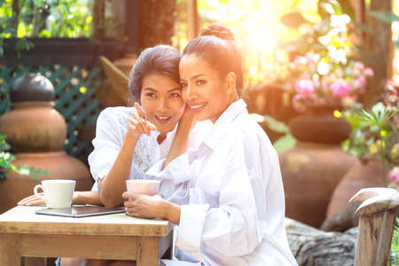Friends bursting out laughing while having coffee in the gardenの写真素材