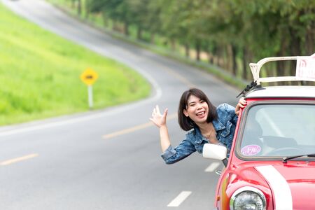 Woman in car road trip waving out the window smilingの写真素材