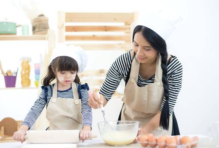 Mother and child daughter girl are cooking cookies and having fun in the kitchen.の写真素材