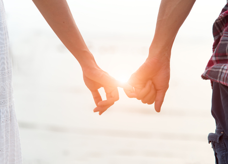 Young couple in love, Attractive man and woman enjoying romantic evening on the beach, Holding hands watching the sunsetの写真素材