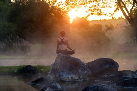 Silhouette of a beautiful Yoga woman in the morning at the hot spring parkの写真素材