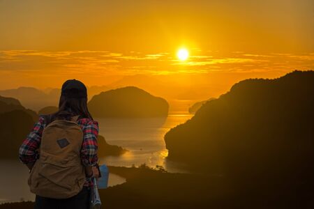 Traveler women with map travel see the mountain veiw in the sunriseの写真素材