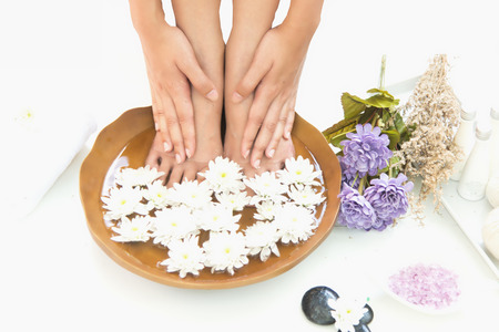 Spa treatment and product for hand and foot spa with flowers and water, wooden background; select and soft focusの写真素材