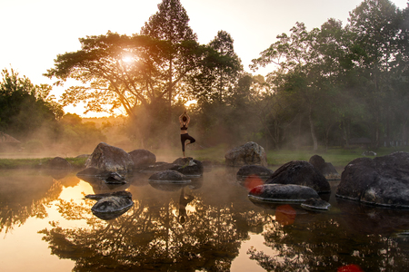Silhouette of a beautiful Yoga woman in the morning at the hot spring parkの写真素材