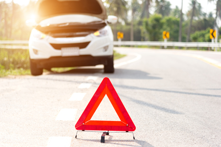 Red emergency stop sign and broken silver car on the roadの写真素材