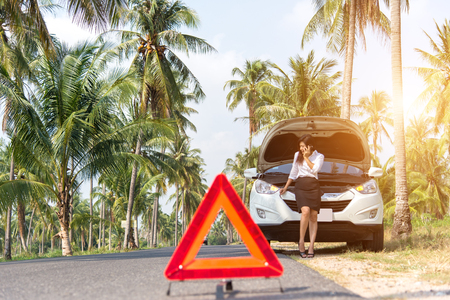 Business woman with a broken car calling for assistance.の写真素材