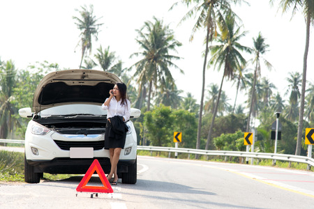 Business woman with a broken car calling for assistanceの写真素材