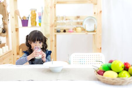 Cute little girl with milk mustache holding glass of milkの写真素材