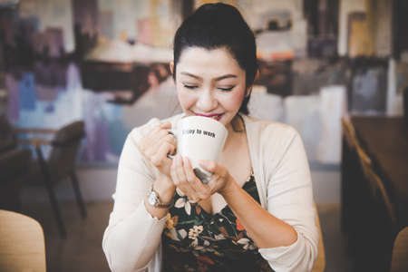 Asian woman drinking coffee in vintage color toneの写真素材
