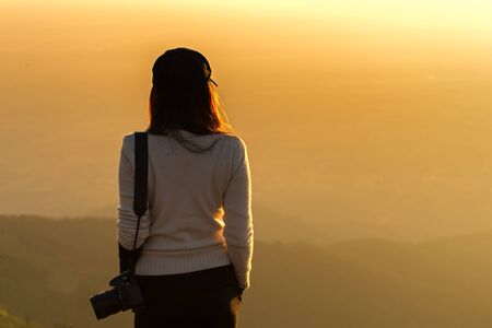 Professional woman photographer see the mountain veiw in the sunriseの写真素材