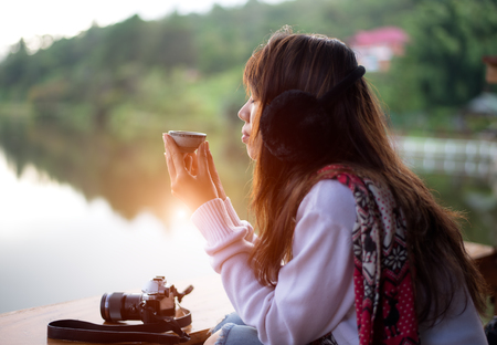 Young woman's hand holding cup of tea on a cold and morning dayの写真素材