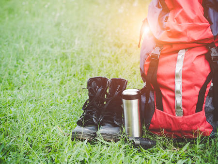 Hiking travel gear on glasses. Items include hiking boots, cup, map,binoculars. Flat lay of outdoor travel equipment items for mountain camping trip.の写真素材